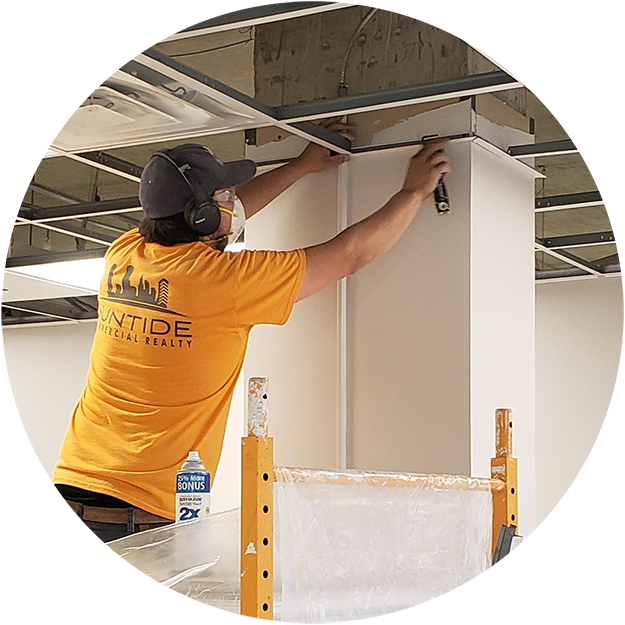 photo of a Suntide construction worker on a ladder, getting ready to add ceiling tiles