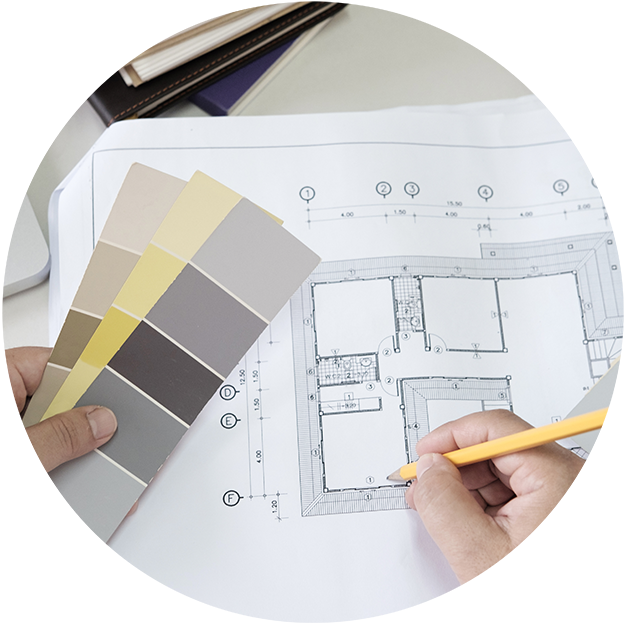 close up of a floor plan with a person's hand holding color samples and making notes on the page